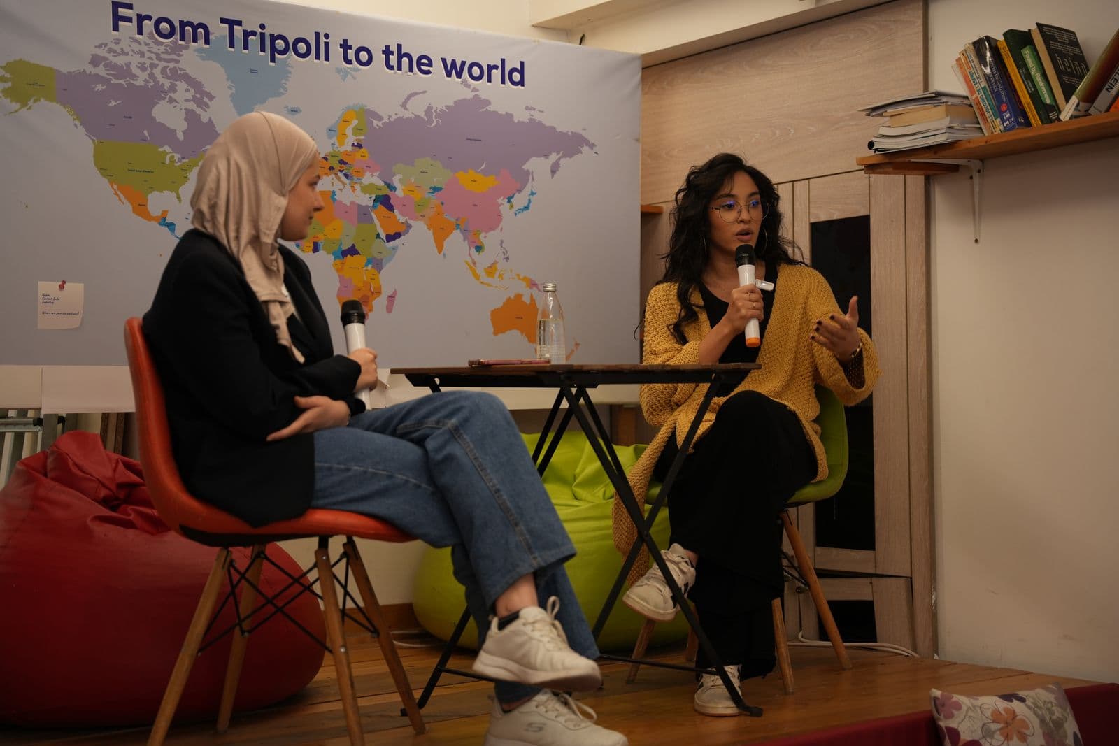 Two women in conversation with microphones in front of a 'From Tripoli to the world' map during JadwaTalks
