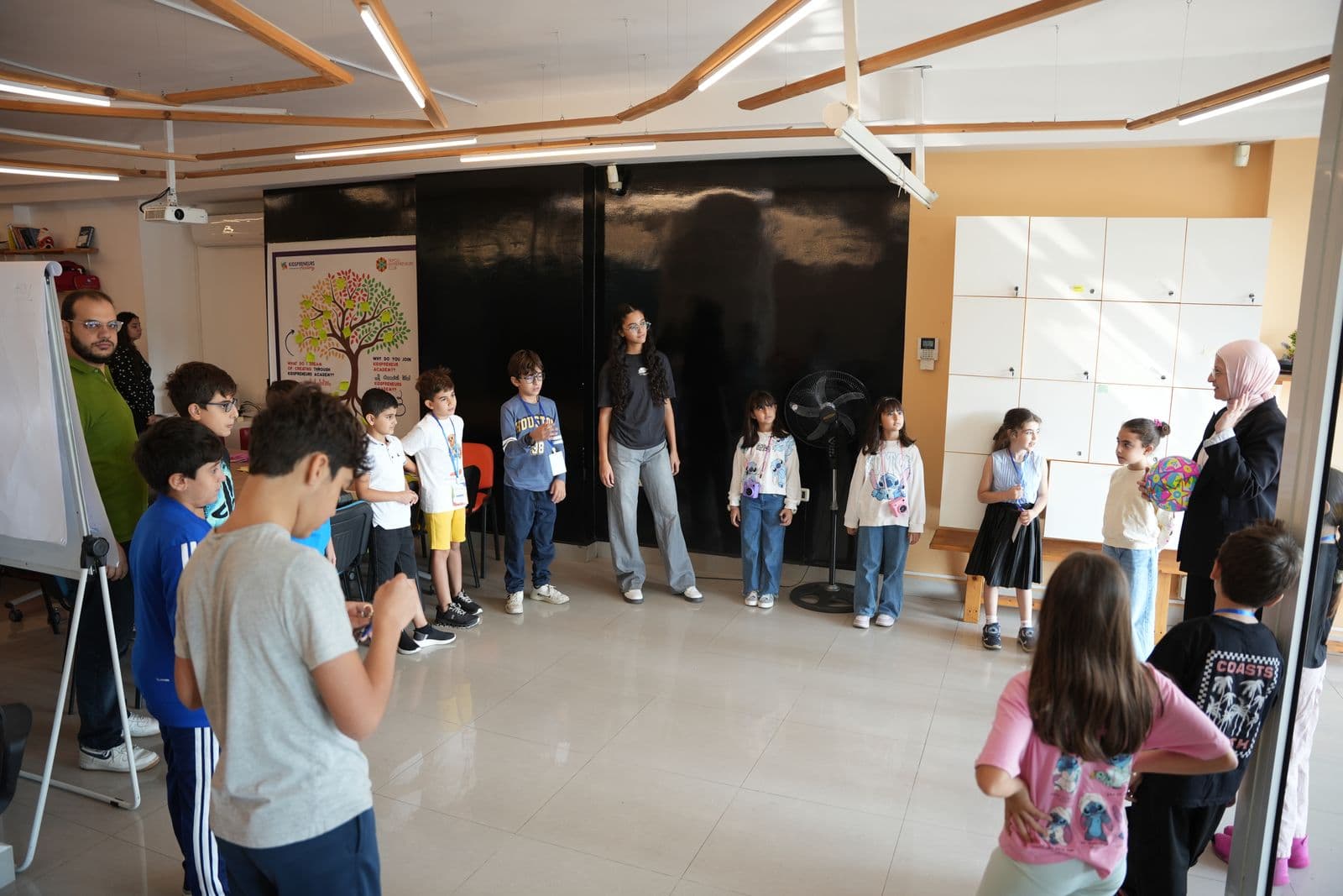 Children and facilitators standing in a large circle during a Youngpreneurs Academy group activity