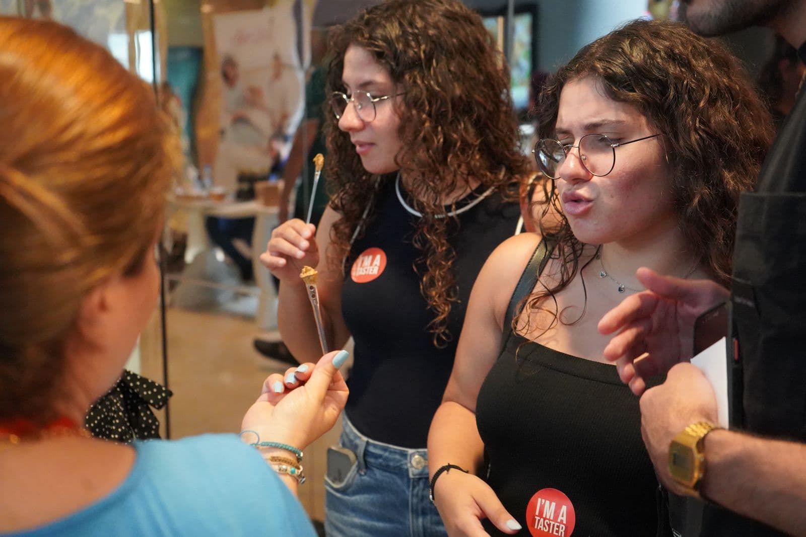 Visitors taste product samples with small spoons at the Gourmet Market