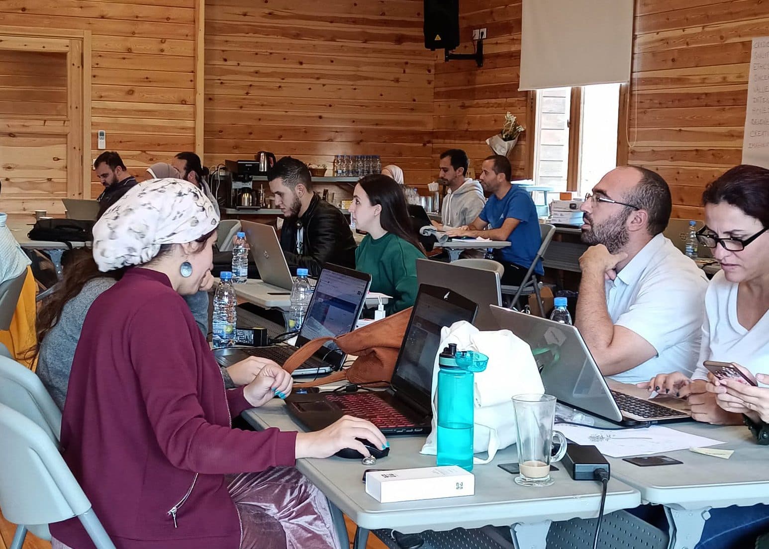 Business owners work on laptops at long tables during a workshop