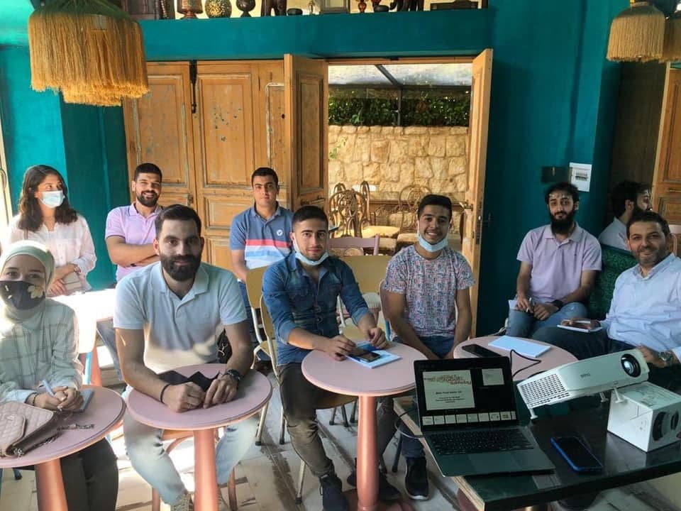 Business owners seated at small tables in a training room