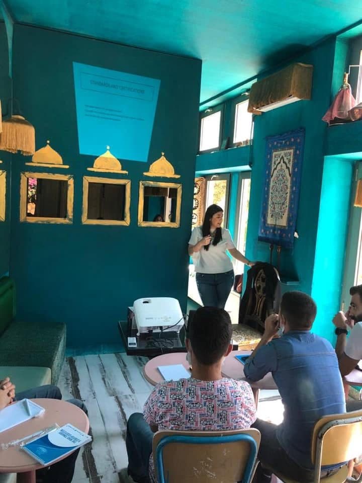 A trainer presents to business owners in a teal-walled room