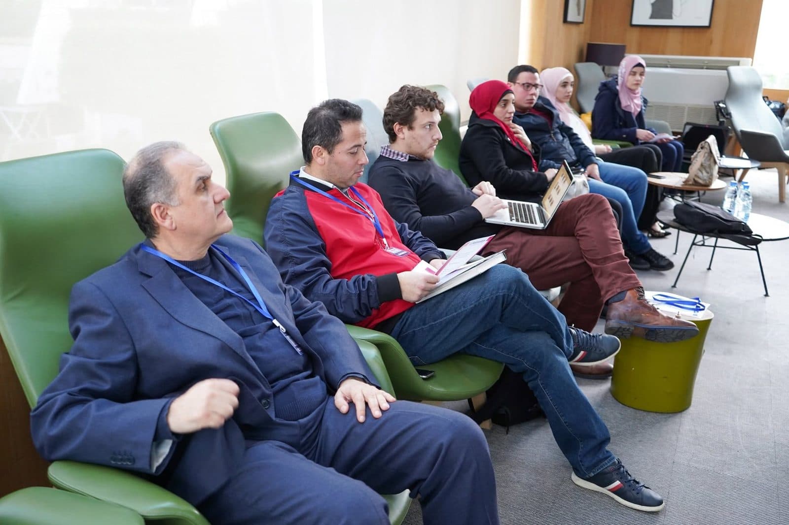 Participants in green armchairs listen to a session