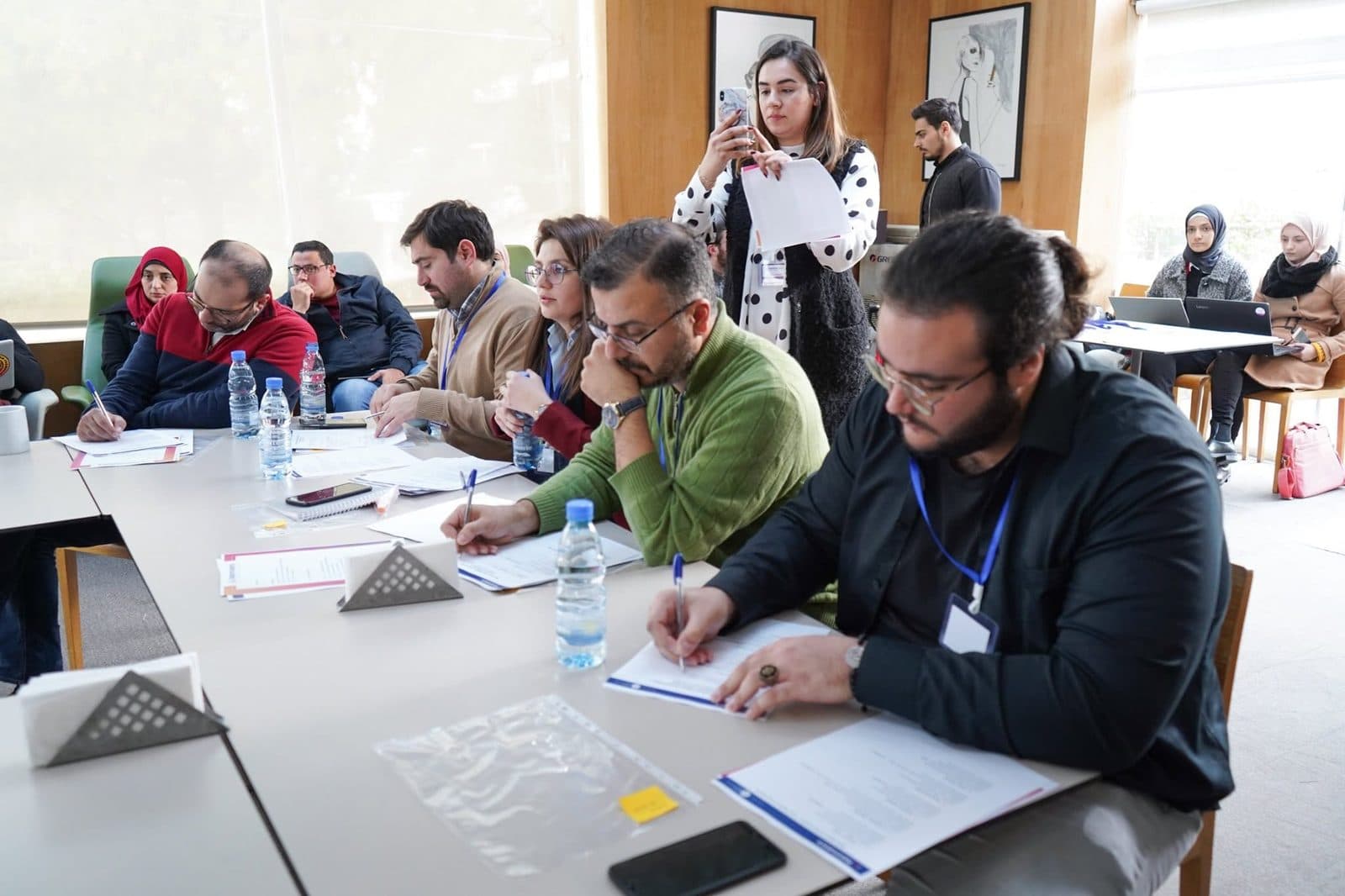 Participants take notes at a long table during a training session