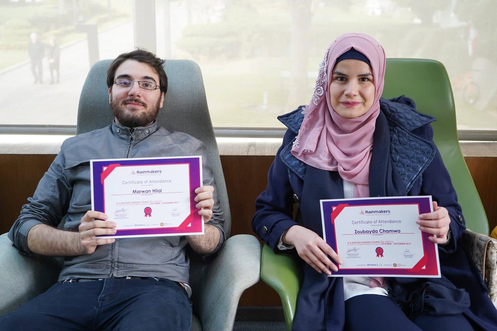 Two graduates hold up their Rainmakers certificates