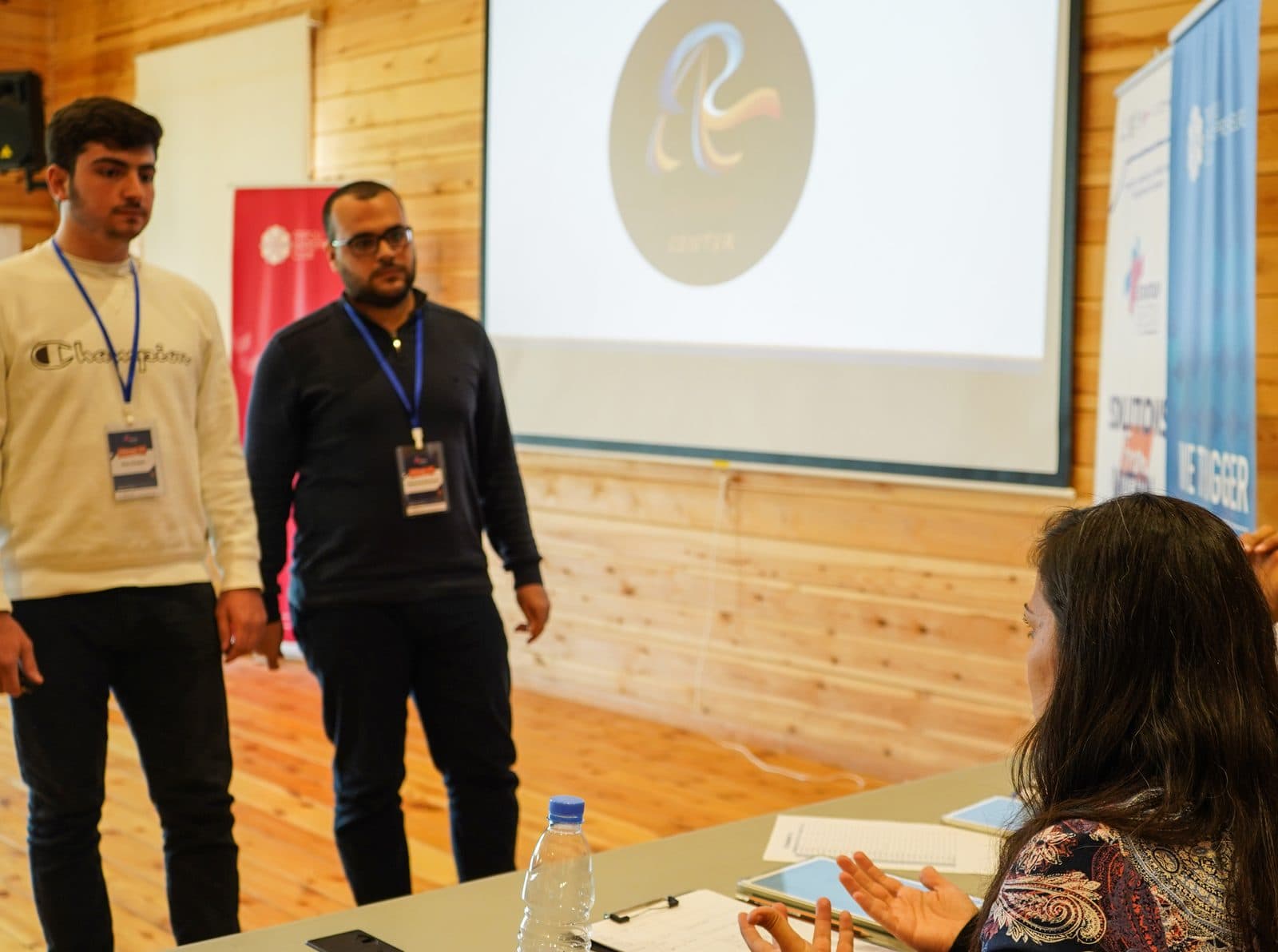 Two founders present their startup to a seated jury