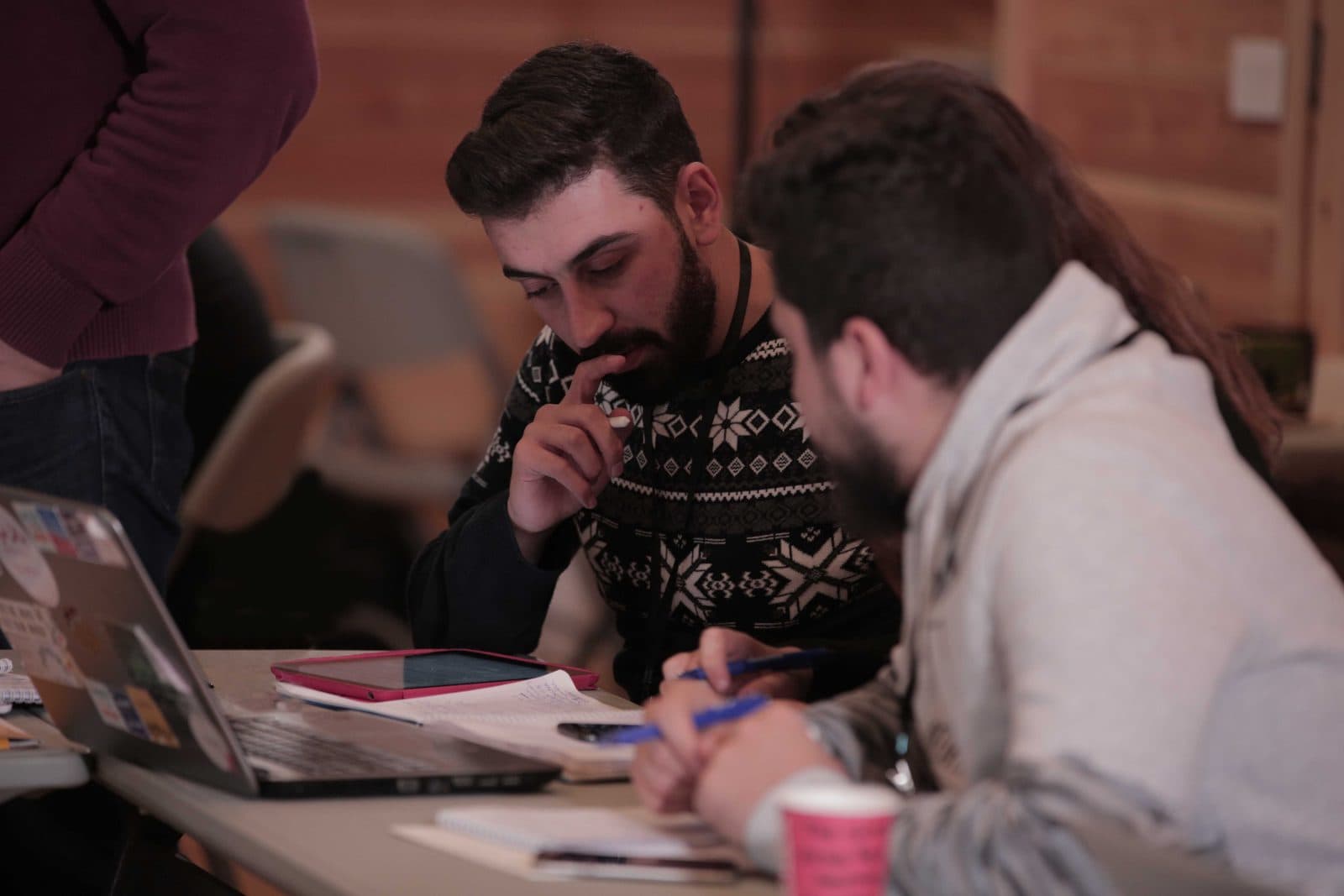 Two founders take notes while working on their business plan