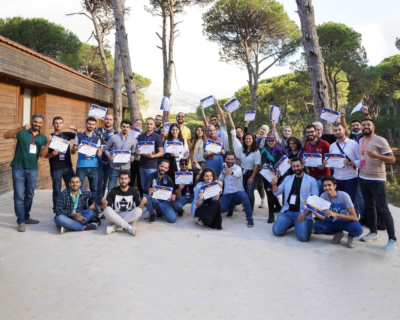 Graduates hold up their certificates and cheer in a group photo