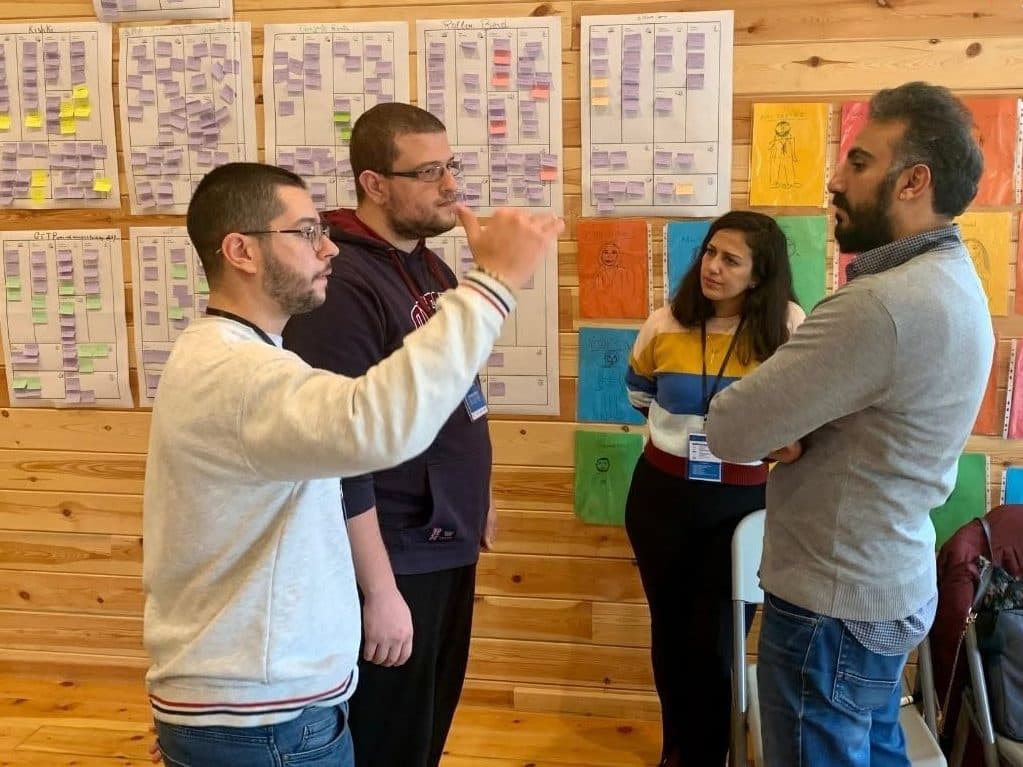 Mentors and founders discuss ideas in front of a wall of sticky notes