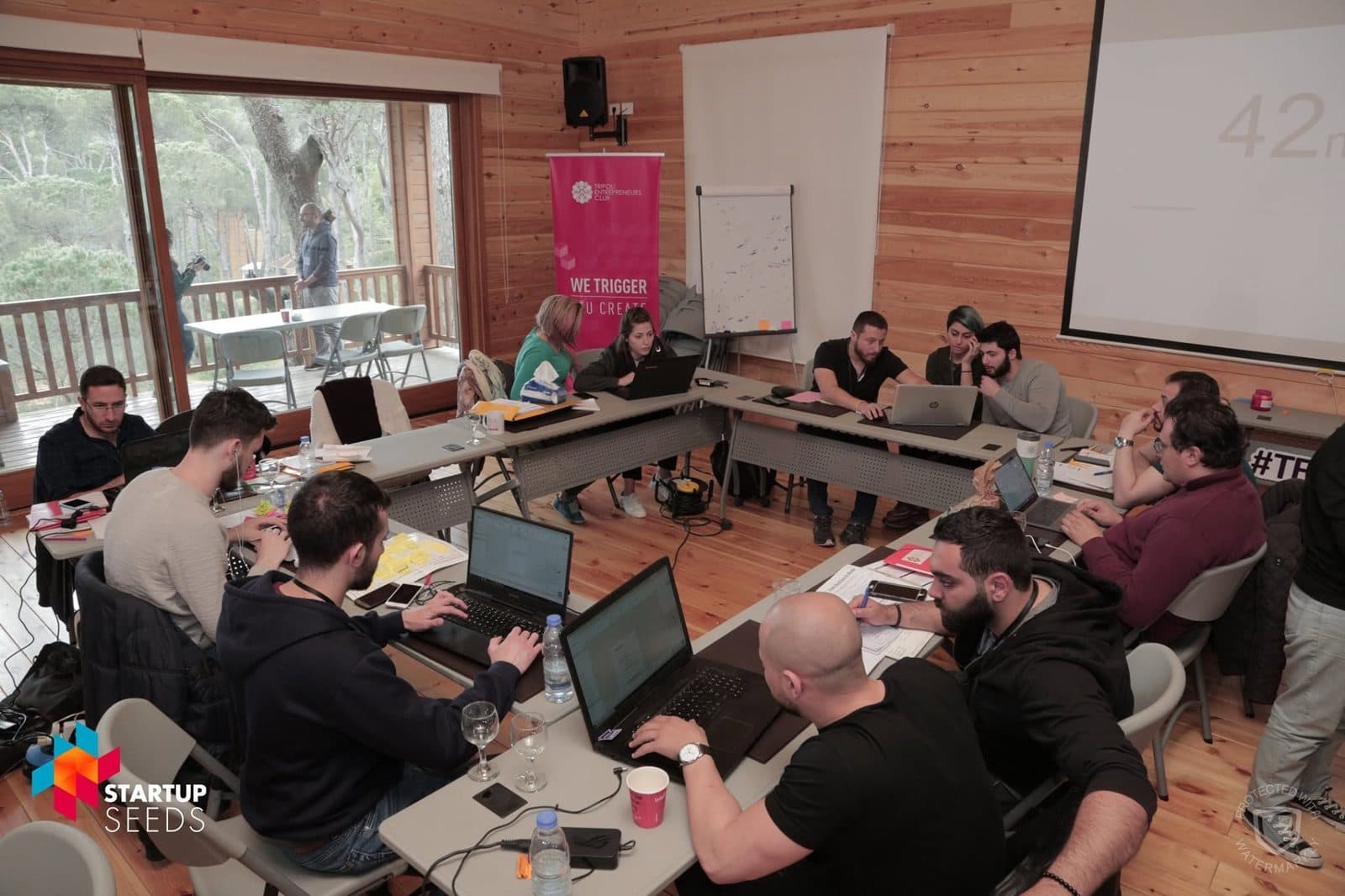 Startup teams work on laptops at tables during the bootcamp