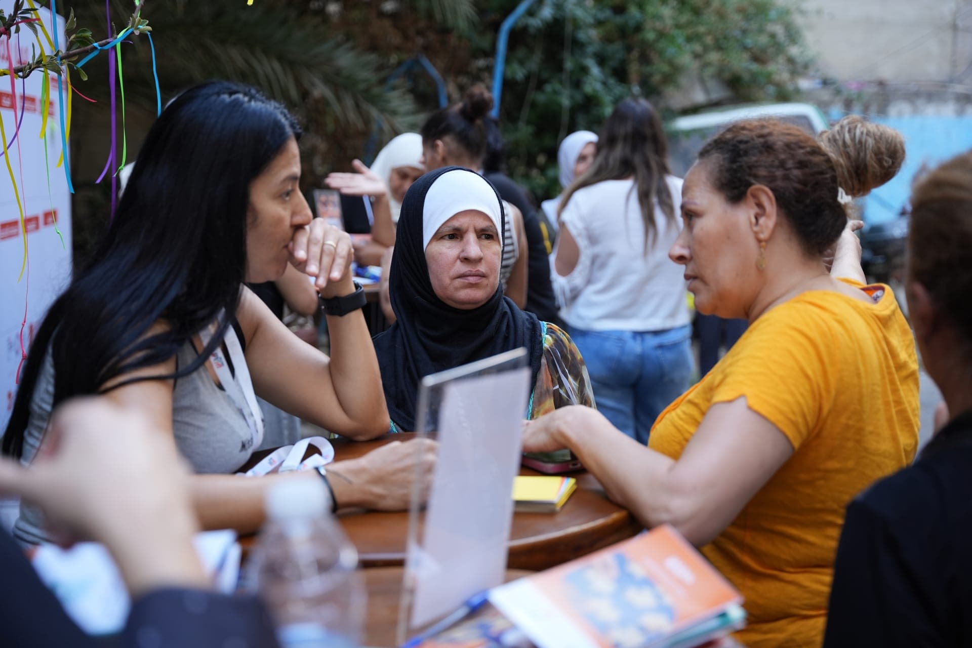 Women talk around a table during an outdoor Haretna activity